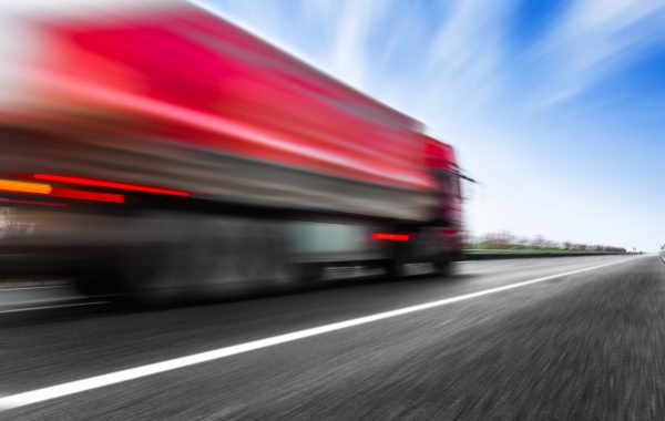 Camión rojo andando muy rápido sobre carretera.